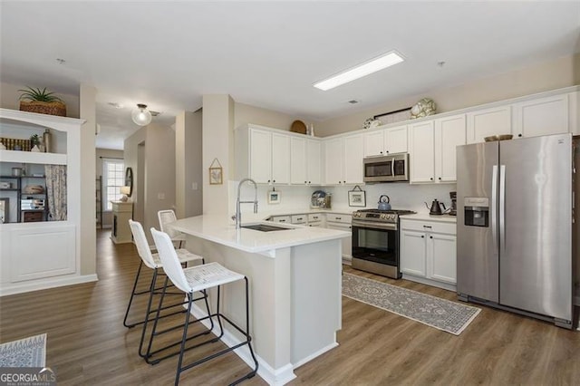 kitchen featuring appliances with stainless steel finishes, sink, white cabinets, and dark hardwood / wood-style floors