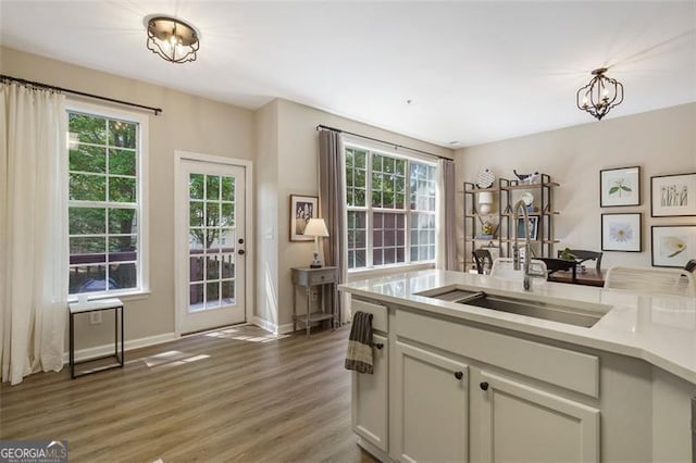 kitchen featuring dark hardwood / wood-style flooring, sink, pendant lighting, and a chandelier