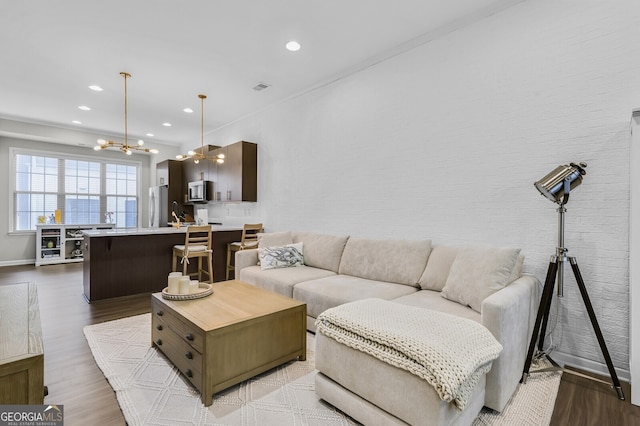 living room with an inviting chandelier, sink, and light hardwood / wood-style flooring