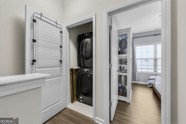 washroom with dark wood-type flooring and stacked washer / dryer