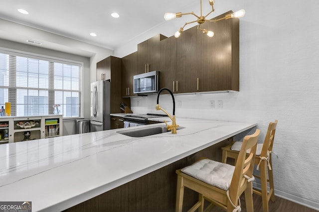 kitchen with stainless steel appliances, a kitchen breakfast bar, light stone counters, dark hardwood / wood-style flooring, and kitchen peninsula