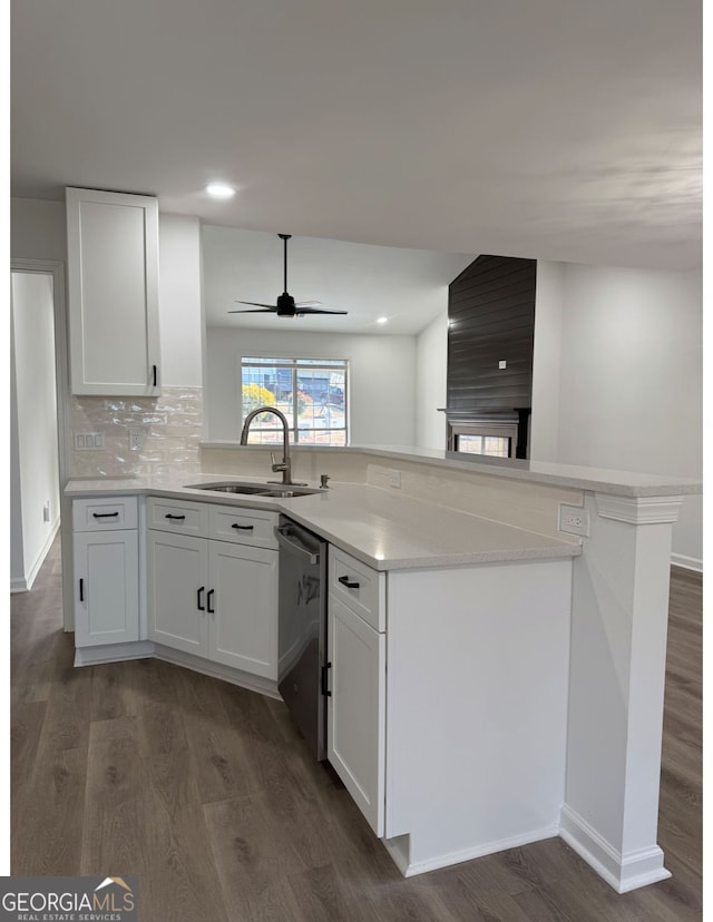 kitchen with sink, white cabinets, backsplash, stainless steel dishwasher, and kitchen peninsula