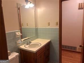 bathroom featuring vanity, toilet, wood-type flooring, and tile walls