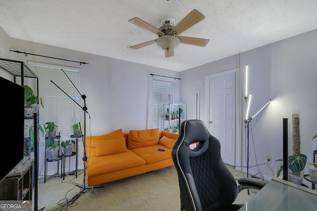 office area with a ceiling fan, light carpet, and a textured ceiling