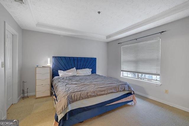 bedroom featuring a tray ceiling, light carpet, a textured ceiling, and baseboards