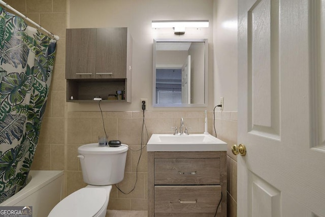 full bath featuring toilet, shower / bath combo with shower curtain, tile walls, and vanity