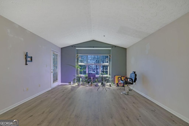 unfurnished room featuring light wood-type flooring, baseboards, a textured ceiling, and lofted ceiling