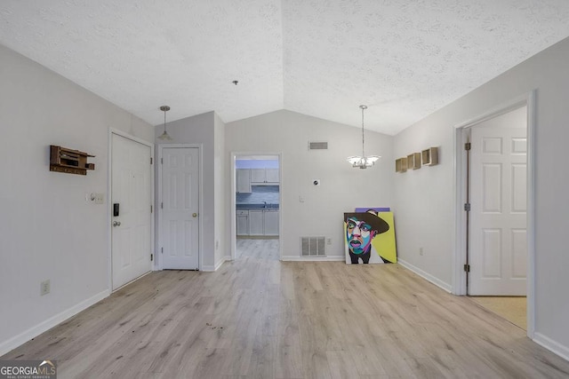 unfurnished dining area with lofted ceiling, light wood-style floors, and visible vents