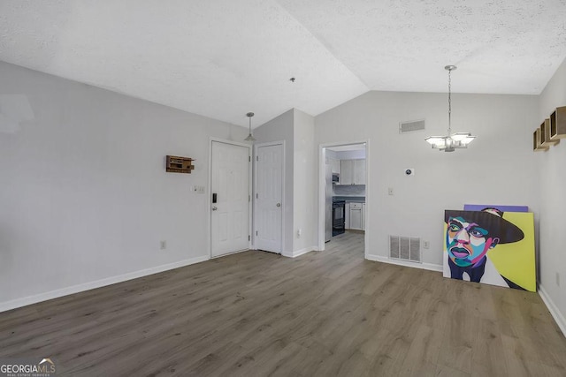 unfurnished dining area with lofted ceiling, visible vents, baseboards, and wood finished floors