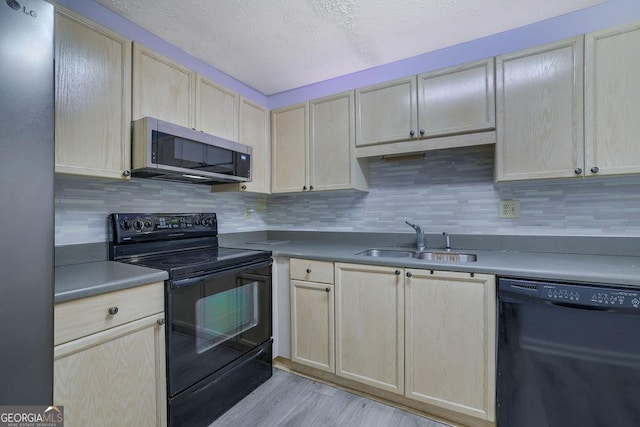 kitchen with black appliances, light brown cabinetry, a sink, and tasteful backsplash