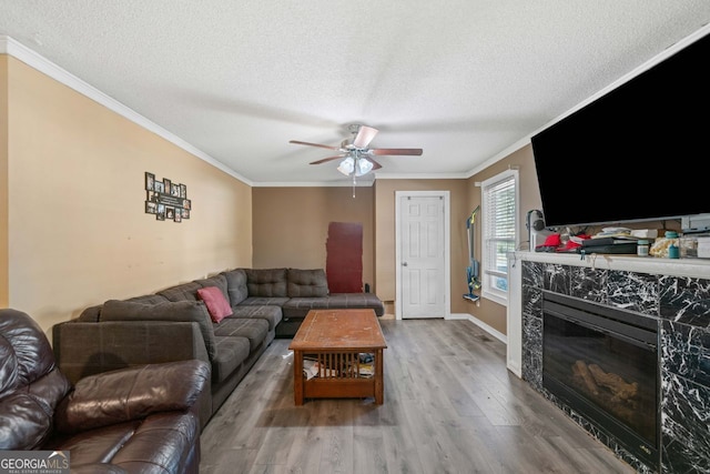 living room featuring ornamental molding, a high end fireplace, a textured ceiling, and light wood-type flooring