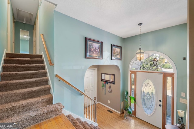 foyer entrance featuring a towering ceiling, light hardwood / wood-style flooring, and a textured ceiling