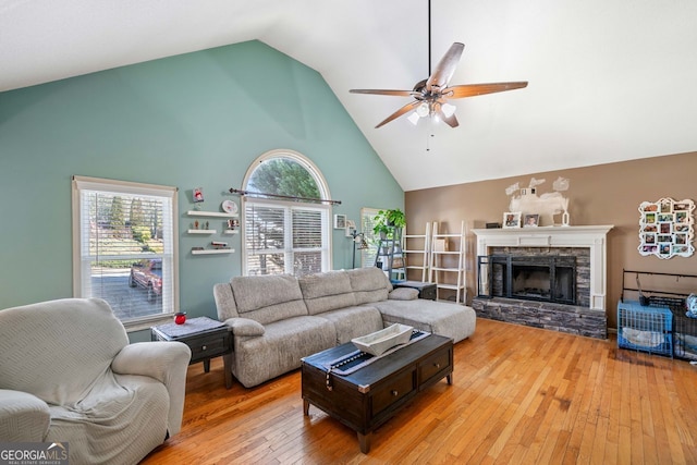 living room featuring ceiling fan, high vaulted ceiling, a fireplace, and hardwood / wood-style floors