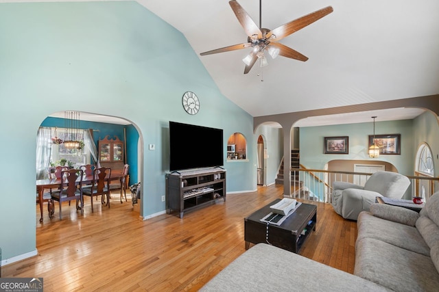 living room with ceiling fan with notable chandelier, wood-type flooring, and high vaulted ceiling