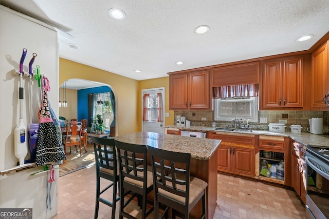 kitchen featuring appliances with stainless steel finishes, tasteful backsplash, sink, a center island, and light stone counters