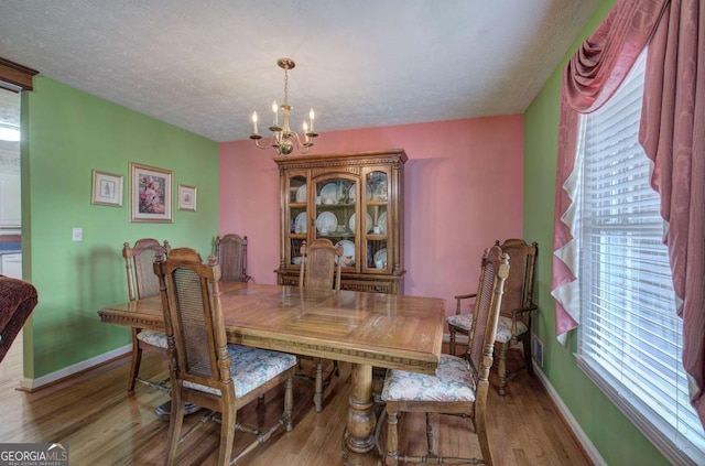 dining room with wood-type flooring, a notable chandelier, and a textured ceiling