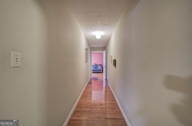 hallway featuring hardwood / wood-style flooring and a textured ceiling