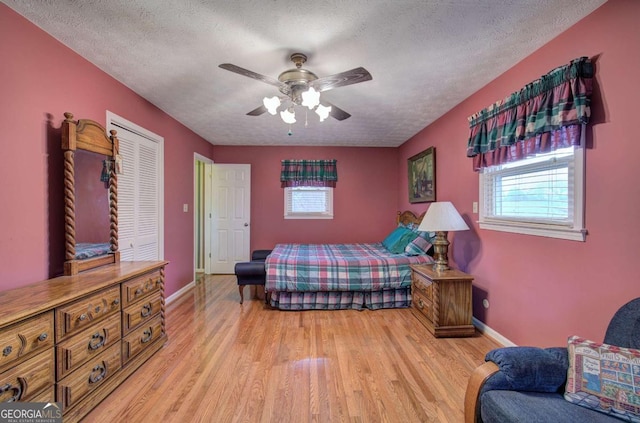 bedroom with a closet, a textured ceiling, ceiling fan, and light hardwood / wood-style flooring