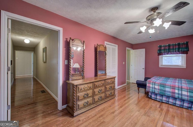 bedroom featuring a textured ceiling, ceiling fan, and light wood-type flooring