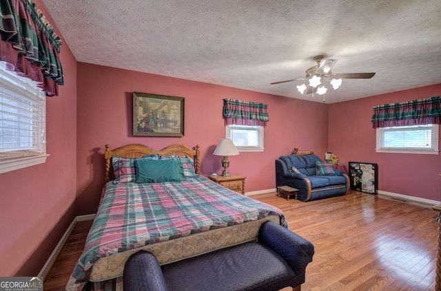 bedroom featuring ceiling fan, light hardwood / wood-style floors, and a textured ceiling