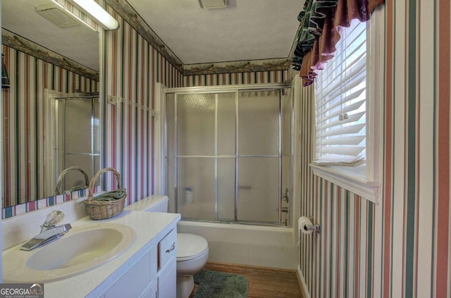 full bathroom featuring hardwood / wood-style floors, enclosed tub / shower combo, vanity, toilet, and a textured ceiling