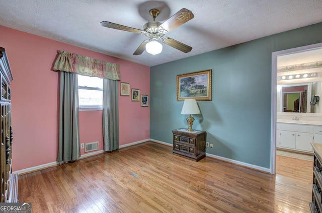 interior space featuring ceiling fan, sink, a textured ceiling, and light wood-type flooring