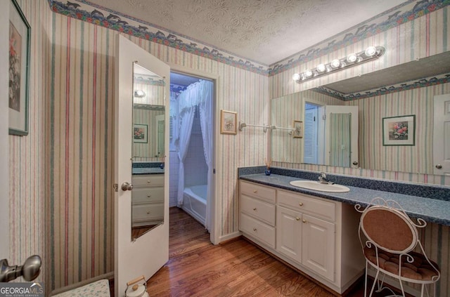 bathroom with hardwood / wood-style flooring, vanity, a bathing tub, and a textured ceiling