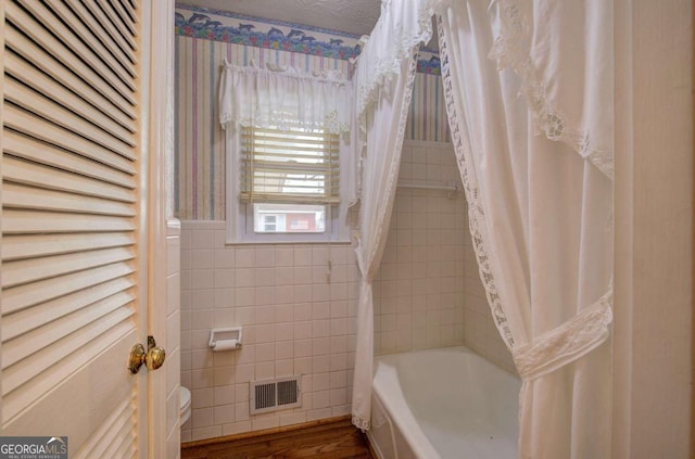 bathroom featuring shower / bath combination with curtain, hardwood / wood-style floors, and a textured ceiling