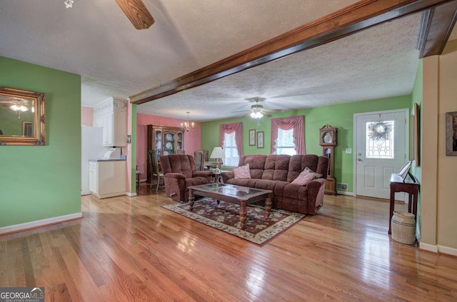 living room featuring ceiling fan with notable chandelier, a textured ceiling, and light hardwood / wood-style flooring