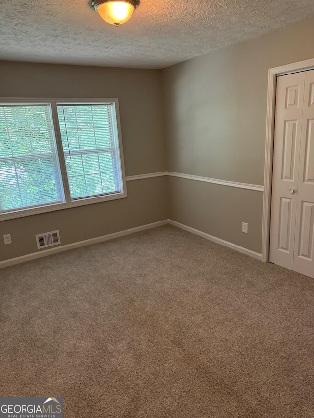 unfurnished room featuring carpet floors and a textured ceiling