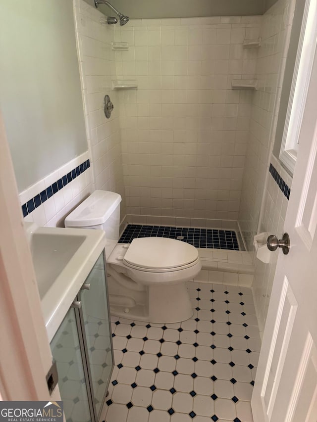 bathroom featuring a tile shower, tile walls, tile patterned floors, and toilet