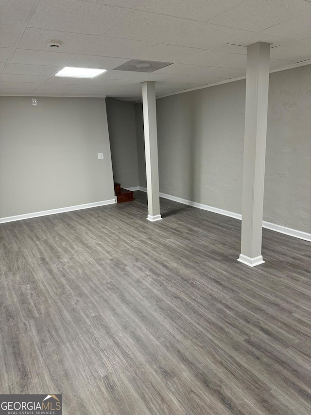 basement with dark hardwood / wood-style flooring and a drop ceiling