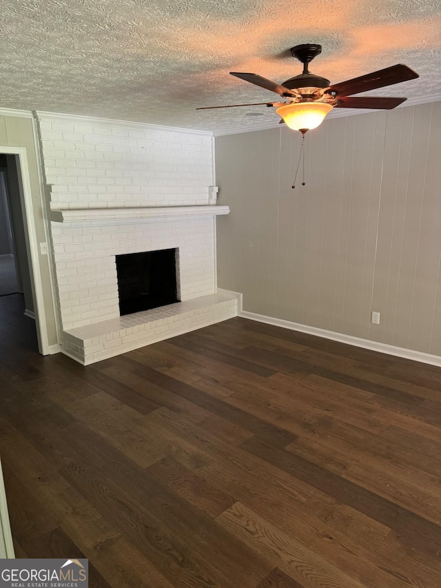 unfurnished living room with ceiling fan, dark hardwood / wood-style floors, a fireplace, a textured ceiling, and wood walls