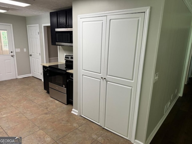 kitchen with stainless steel appliances, light tile patterned floors, and a textured ceiling