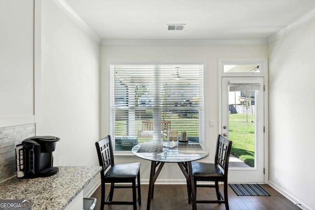 dining space with ornamental molding and dark wood-type flooring