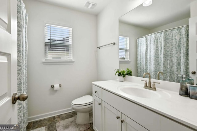 bathroom featuring vanity, toilet, and a healthy amount of sunlight