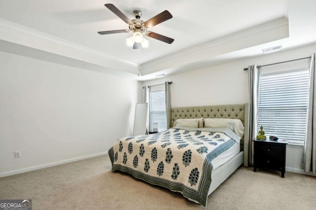 bedroom with ceiling fan, a tray ceiling, and multiple windows