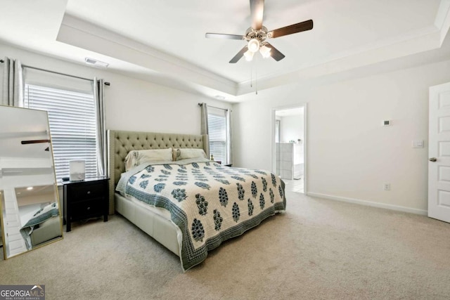 bedroom with ceiling fan, a tray ceiling, light carpet, and multiple windows