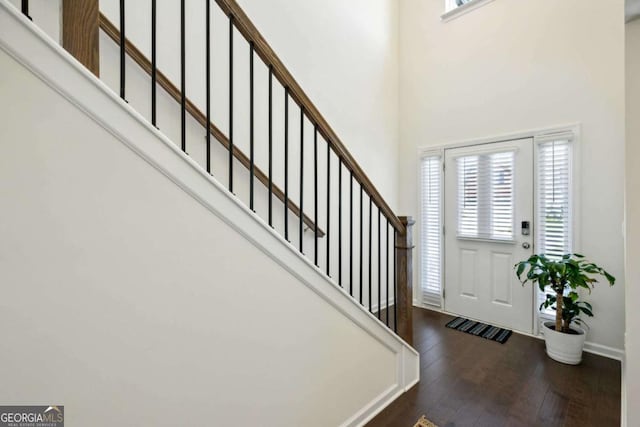 entryway with dark wood-type flooring and a towering ceiling