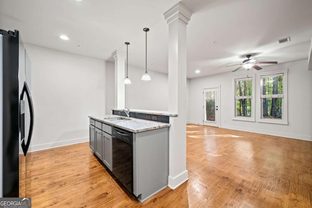 kitchen featuring pendant lighting, decorative columns, sink, black appliances, and light stone countertops