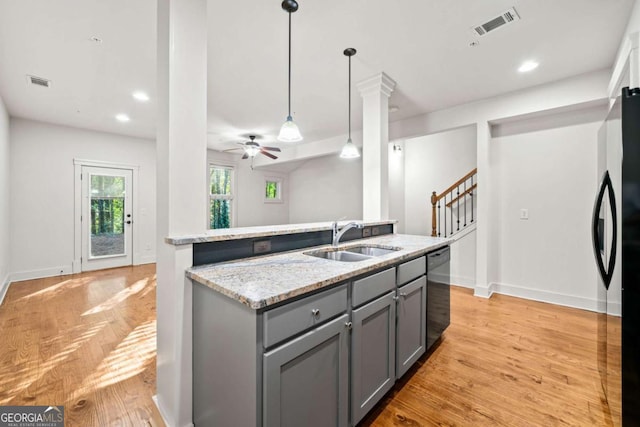 kitchen with sink, gray cabinetry, hanging light fixtures, light stone countertops, and light wood-type flooring