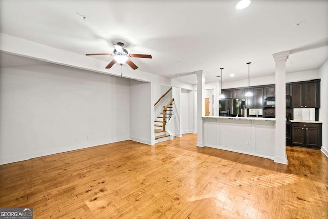 unfurnished living room featuring ceiling fan, light wood-type flooring, and ornate columns