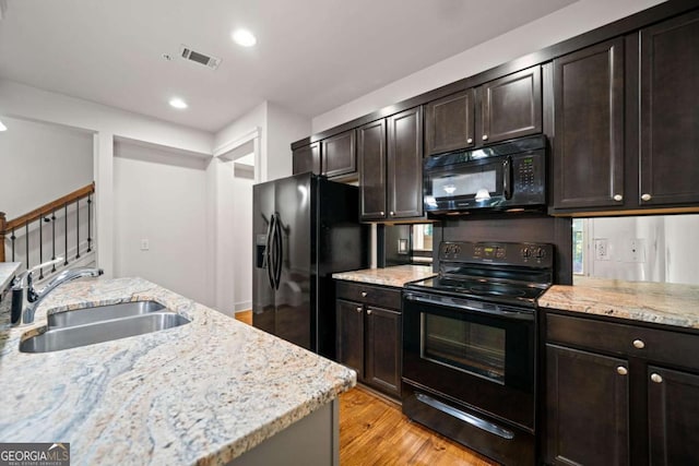 kitchen with dark brown cabinets, sink, light stone counters, and black appliances