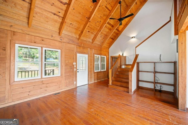 interior space with wood walls, high vaulted ceiling, wooden ceiling, beamed ceiling, and hardwood / wood-style floors