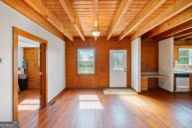 interior space featuring wood ceiling, a healthy amount of sunlight, wooden walls, and beamed ceiling