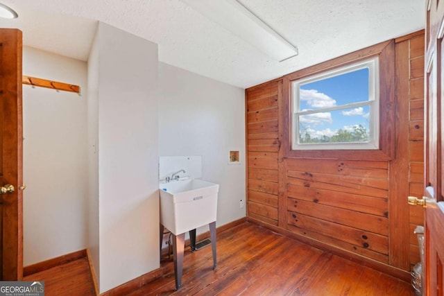 office area with a textured ceiling, dark hardwood / wood-style flooring, and wood walls