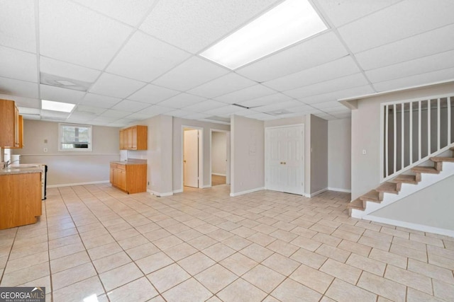 basement featuring a paneled ceiling, sink, and light tile patterned floors