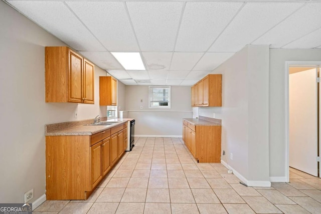 kitchen featuring light tile patterned flooring, a paneled ceiling, dishwasher, and sink