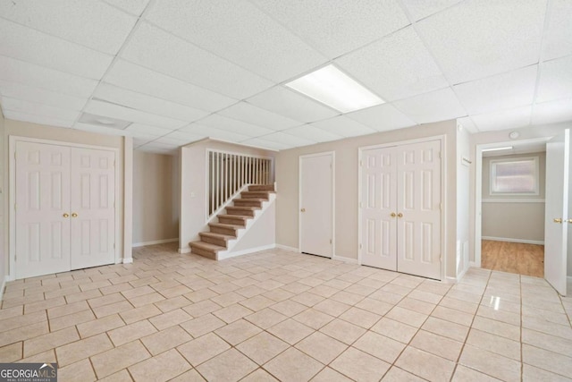 basement with a drop ceiling and light tile patterned flooring