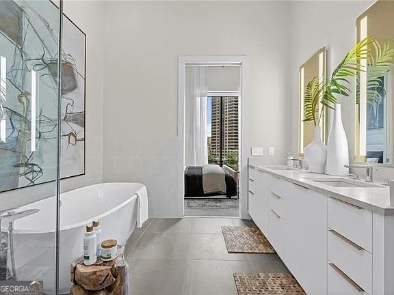 bathroom featuring vanity, a bath, tile patterned flooring, and tile walls